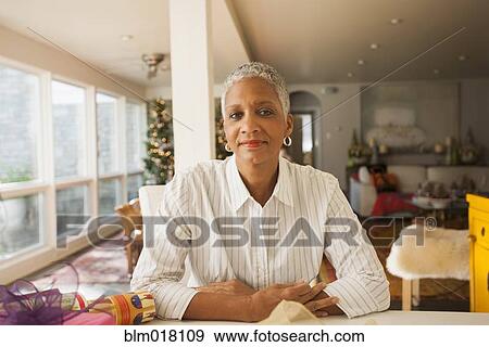 Stock Photo - African American woman sitting at table. Fotosearch