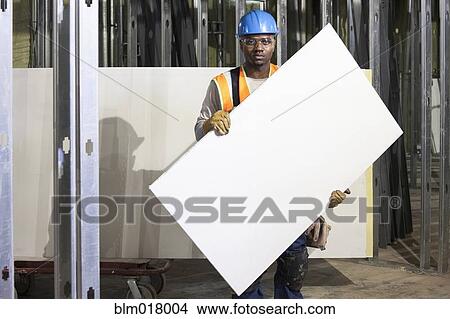 Picture - African American worker holding blank piece of two-by-four.. Fotosearch