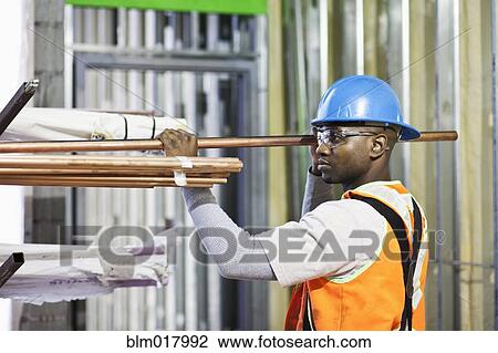 Stock Image - African American worker organizing metal on site. Fotosearch