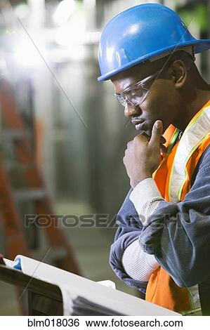 African-American worker reading blueprints on site View Large Photo Image Stock Photograph - African-American worker reading blueprints on site. Fotosearch