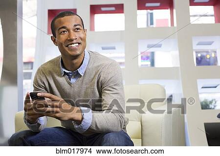 Picture - Black businessman using cell phone in office. Fotosearch