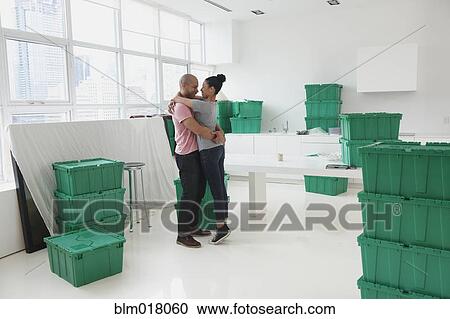 Stock Image - Black couple hugging in new house. Fotosearch