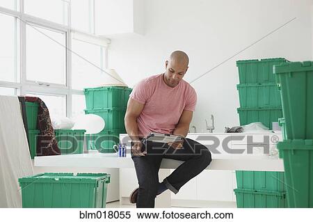 Stock Photography - Black man using tablet computer in new house. Fotosearch