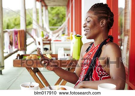 Stock Image - Black woman using cell phone at lunch. Fotosearch