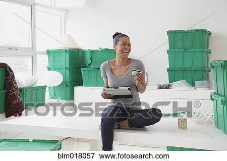 Stock Photo - Black woman using tablet computer in new house. Fotosearch