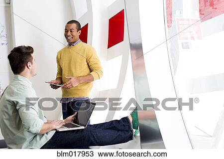 Stock Image - Businessmen talking in office. Fotosearch