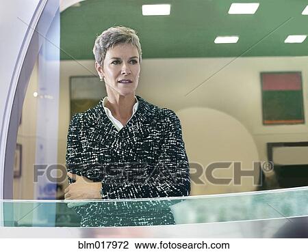 Stock Image - Businesswoman standing at office window. Fotosearch