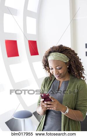 Businesswoman using cell phone in office View Large Photo Image Stock Photography - Businesswoman using cell phone in office. Fotosearch