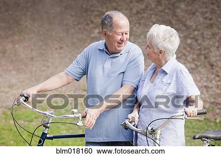 Caucasian couple walking bicycles together View Large Photo Image Stock Image - Caucasian couple walking bicycles together. Fotosearch