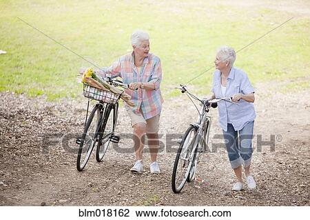 Caucasian couple walking bicycles together View Large Photo Image Stock Image - Caucasian couple walking bicycles together. Fotosearch