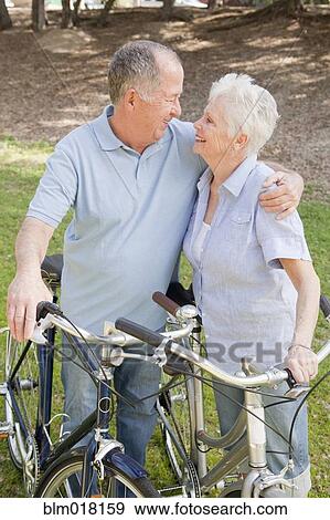 Stock Photo - Caucasian couple walking bicycles together. Fotosearch