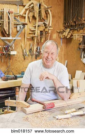 Stock Photo - Caucasian man smiling in wood shop. Fotosearch
