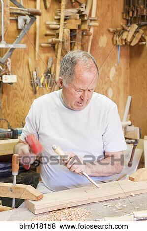Stock Photo - Caucasian man smiling in wood shop. Fotosearch
