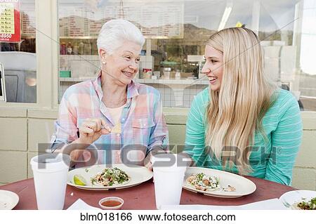 Stock Photograph - Caucasian woman and granddaughter eating together. Fotosearch