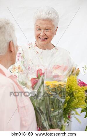 Stock Photo - Caucasian women holding bouquets of flowers. Fotosearch