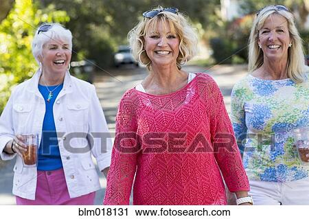 Stock Image - Caucasian women walking on suburban street. Fotosearch