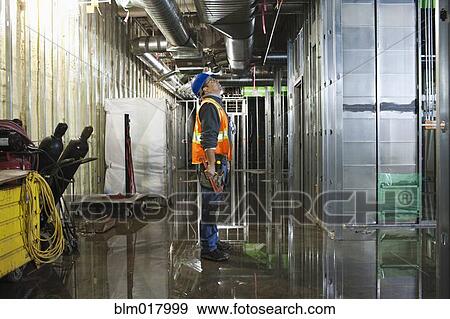 Stock Photo - Caucasian worker measuring metal on site. Fotosearch