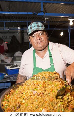 Stock Image - Hispanic cook selling food in market. Fotosearch