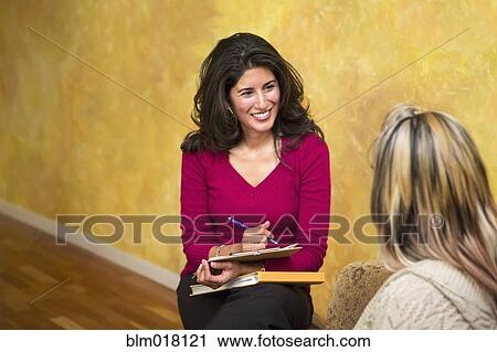 Stock Image - Hispanic women talking indoors. Fotosearch