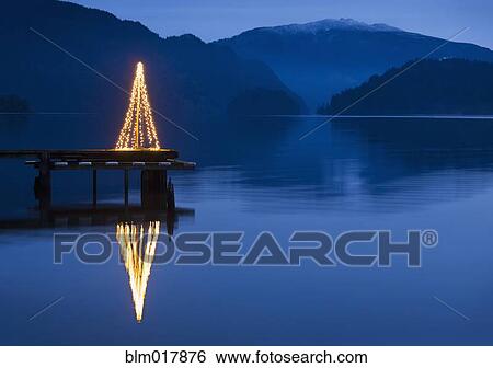 Stock Photograph - Illuminated Christmas tree on wooden pier. Fotosearch