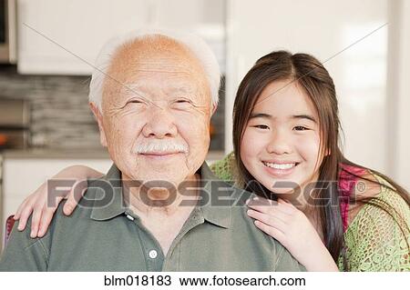 Stock Image - Japanese man and granddaughter smiling. Fotosearch