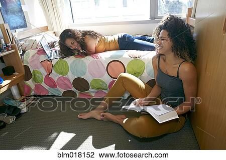 Stock Image - Mixed race college students relaxing in dorm. Fotosearch