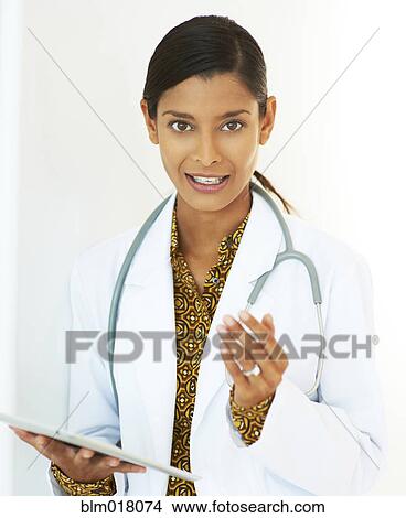 Picture - Mixed race doctor holding tablet computer. Fotosearch