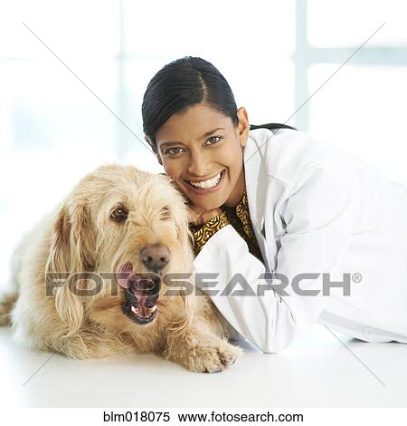 Stock Photography - Mixed race veterinarian smiling with dog. Fotosearch