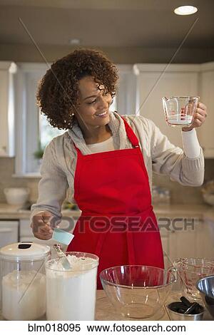 Stock Photography - Mixed race woman baking in kitchen. Fotosearch