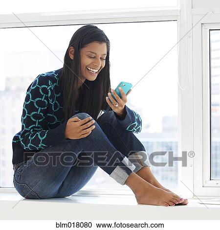 Stock Image - Mixed race woman using cell phone. Fotosearch