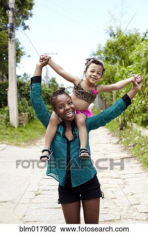 Mother carrying daughter on shoulders View Large Photo Image Stock Image - Mother carrying daughter on shoulders. Fotosearch
