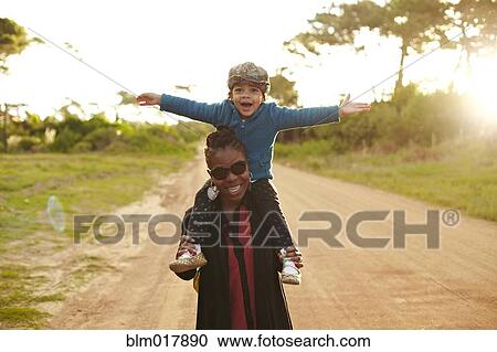 Mother carrying son on shoulders View Large Photo Image Stock Image - Mother carrying son on shoulders. Fotosearch