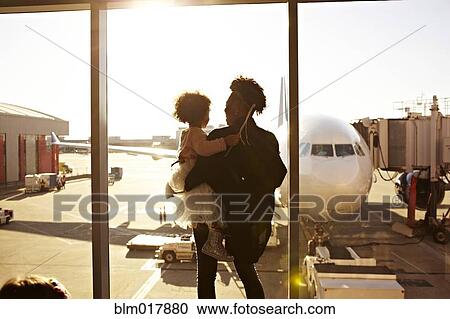 Stock Image - Mother holding daughter at airport. Fotosearch