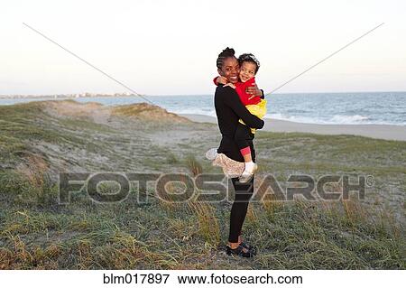Stock Photo - Mother hugging daughter on beach. Fotosearch