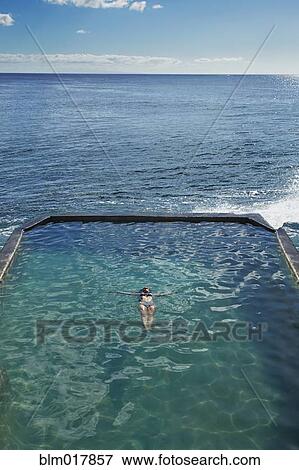Stock Photo - Pacific Islander woman floating in pool. Fotosearch