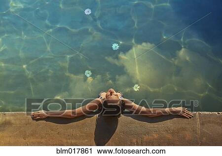 Stock Image - Pacific Islander woman relaxing in pool. Fotosearch