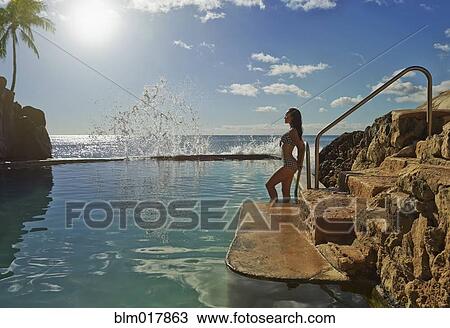 Stock Image - Pacific Islander woman relaxing in pool. Fotosearch