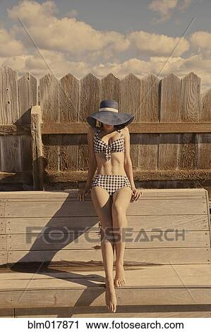 Stock Image - Pacific Islander woman sitting on wooden bench. Fotosearch