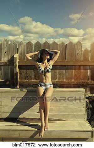 Stock Image - Pacific Islander woman sitting on wooden bench. Fotosearch