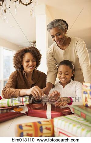 Stock Image - Three generations of women wrapping Christmas presents. Fotosearch