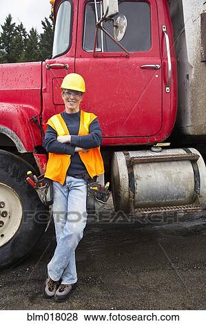 Stock Photo - Worker smiling by truck on site. Fotosearch