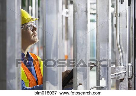 Stock Photo - Worker surveying metal on site. Fotosearch