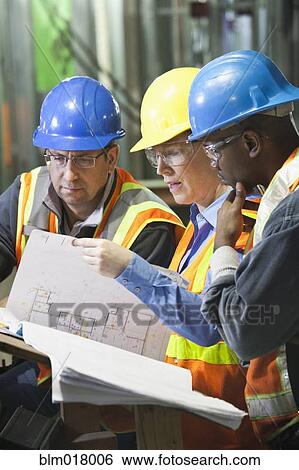 Stock Photograph - Workers reading blueprints on site. Fotosearch