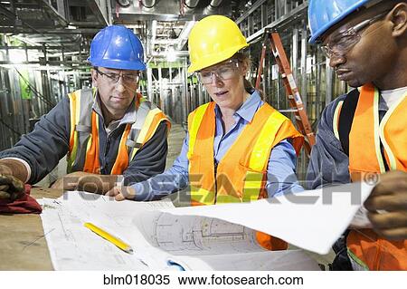 Stock Photography - Workers reading blueprints on site. Fotosearch