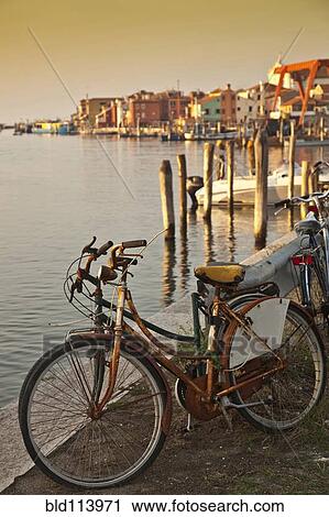 Bicycle parked by urban canal, Venice, Italy View Large Photo Image Stock Image - Bicycle parked by urban canal, Venice, Italy. Fotosearch
