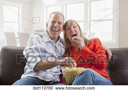 Caucasian couple eating popcorn on sofa View Large Photo Image Stock Image - Caucasian couple eating popcorn on sofa. Fotosearch