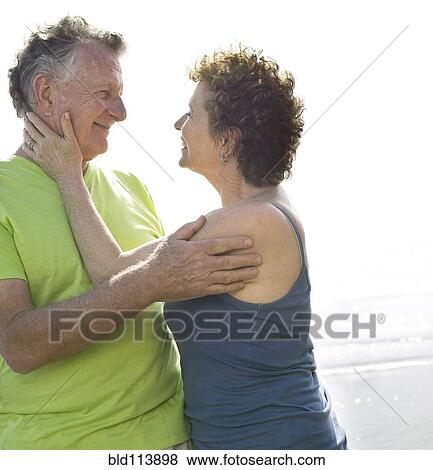 Stock Photo - Caucasian couple hugging on beach. Fotosearch