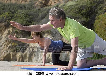 Stock Photography - Caucasian couple practicing yoga on beach. Fotosearch