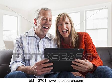 Caucasian couple using tablet computer on sofa View Large Photo Image Stock Image - Caucasian couple using tablet computer on sofa. Fotosearch