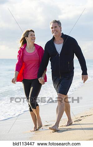 Caucasian couple walking on beach View Large Photo Image Stock Photo - Caucasian couple walking on beach. Fotosearch
